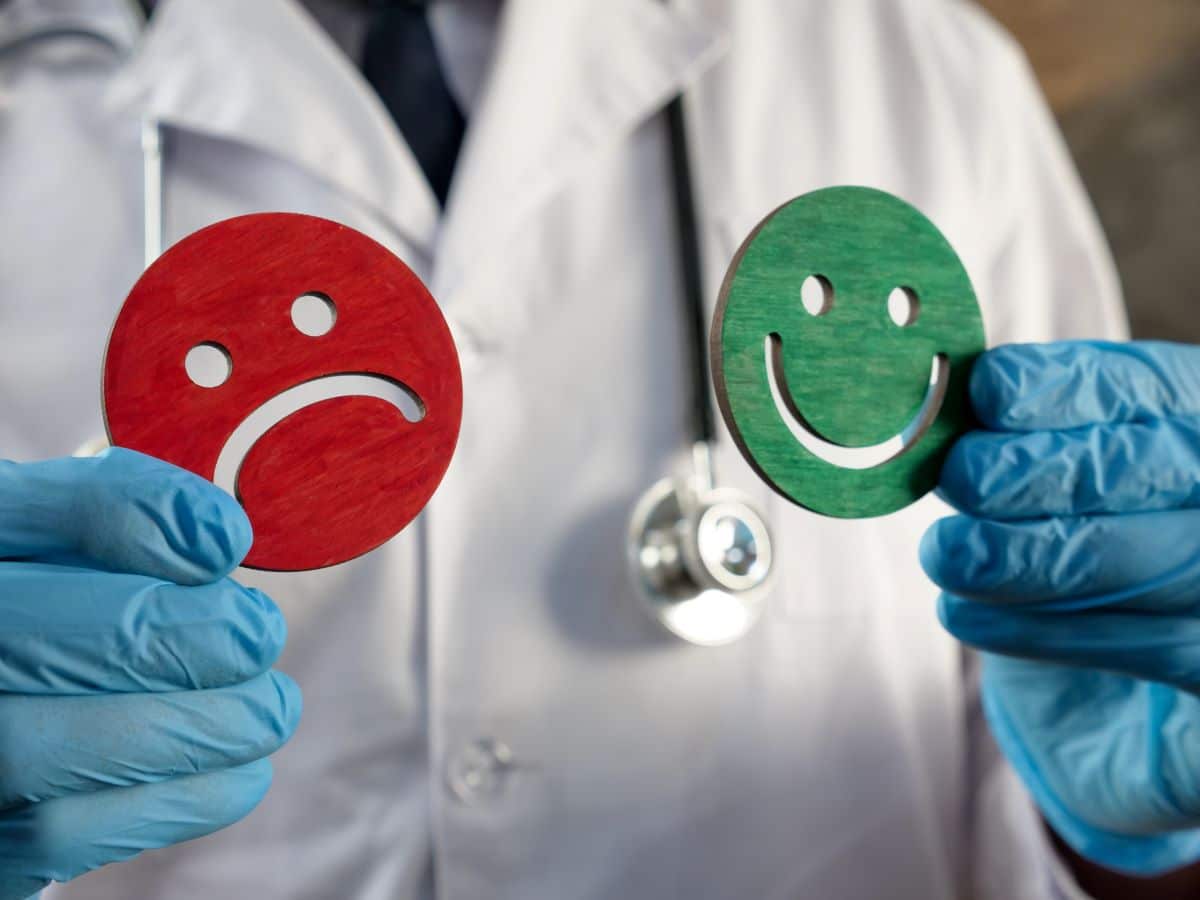 doctor holding sad and smiley faces