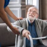 Nurse caring for an elderly man with a walker.