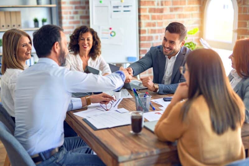 Group of people in a meeting. Two of them are shaking hands.